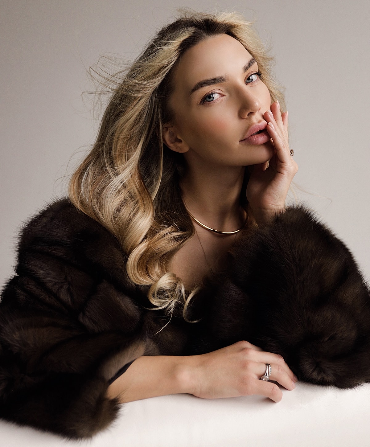Woman in fur coat with elegant hairstyle and jewelry.