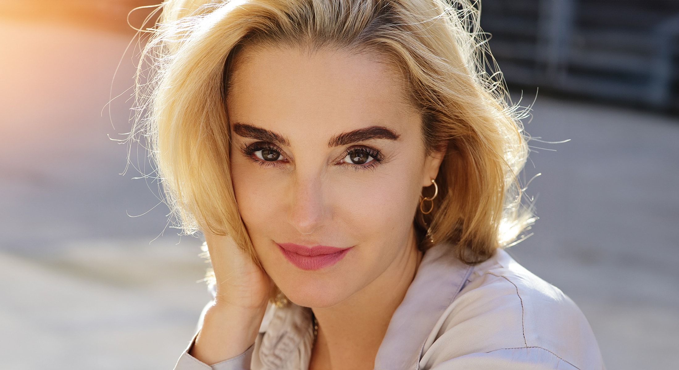 Smiling woman with blonde hair in sunlight.